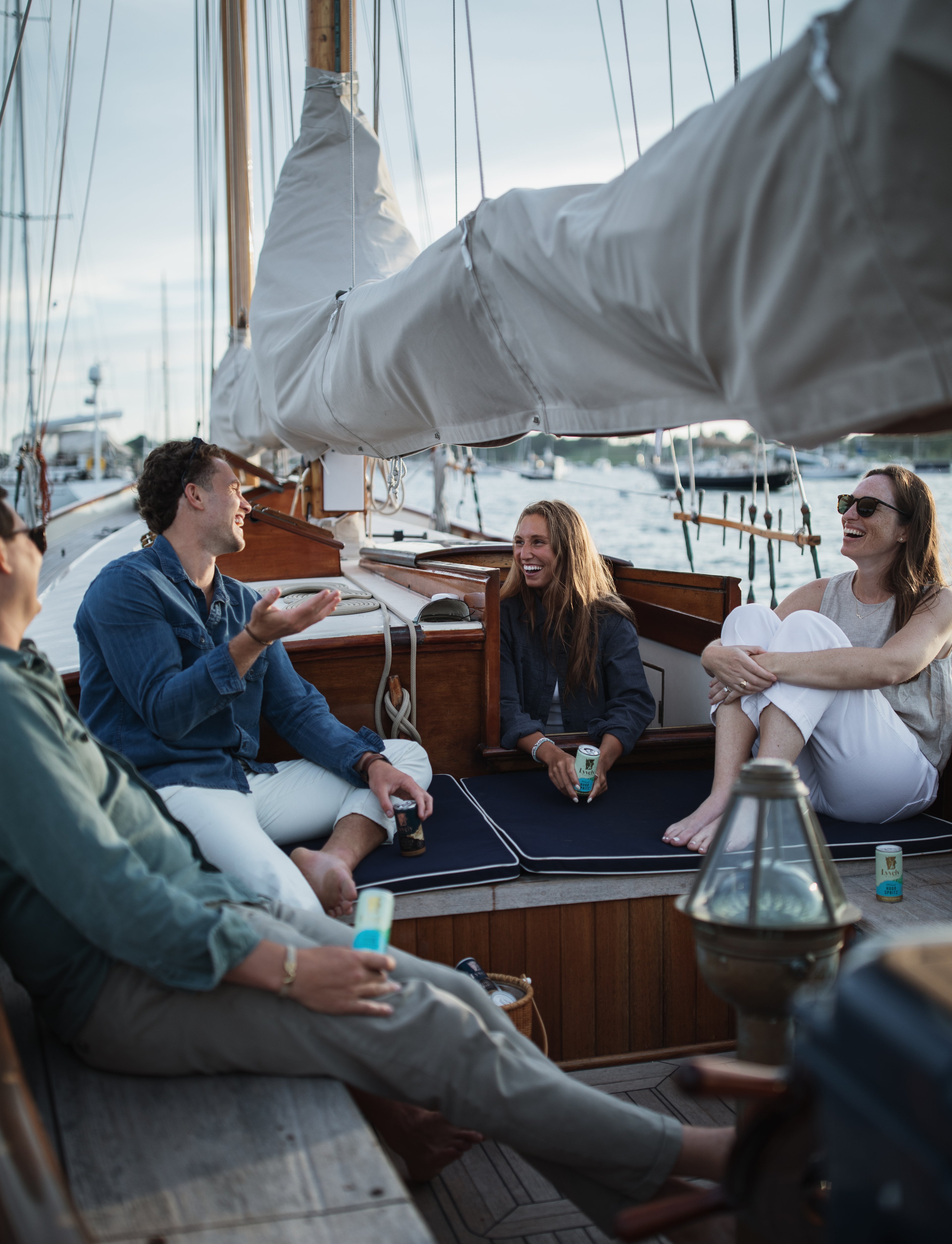 Group of people hanging out on a sailboat with Lyvely Drinks canned espresso martini and canned hugo spritz